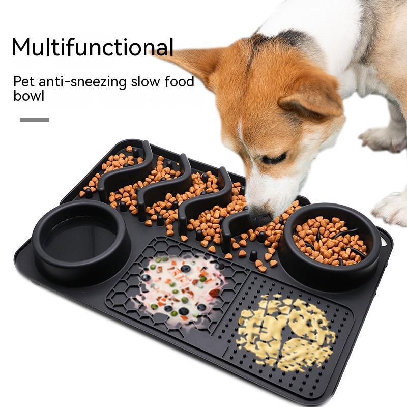 Black silicone dog licking mat with slow feeder ridges, water bowl, and food compartments, dog eating from it